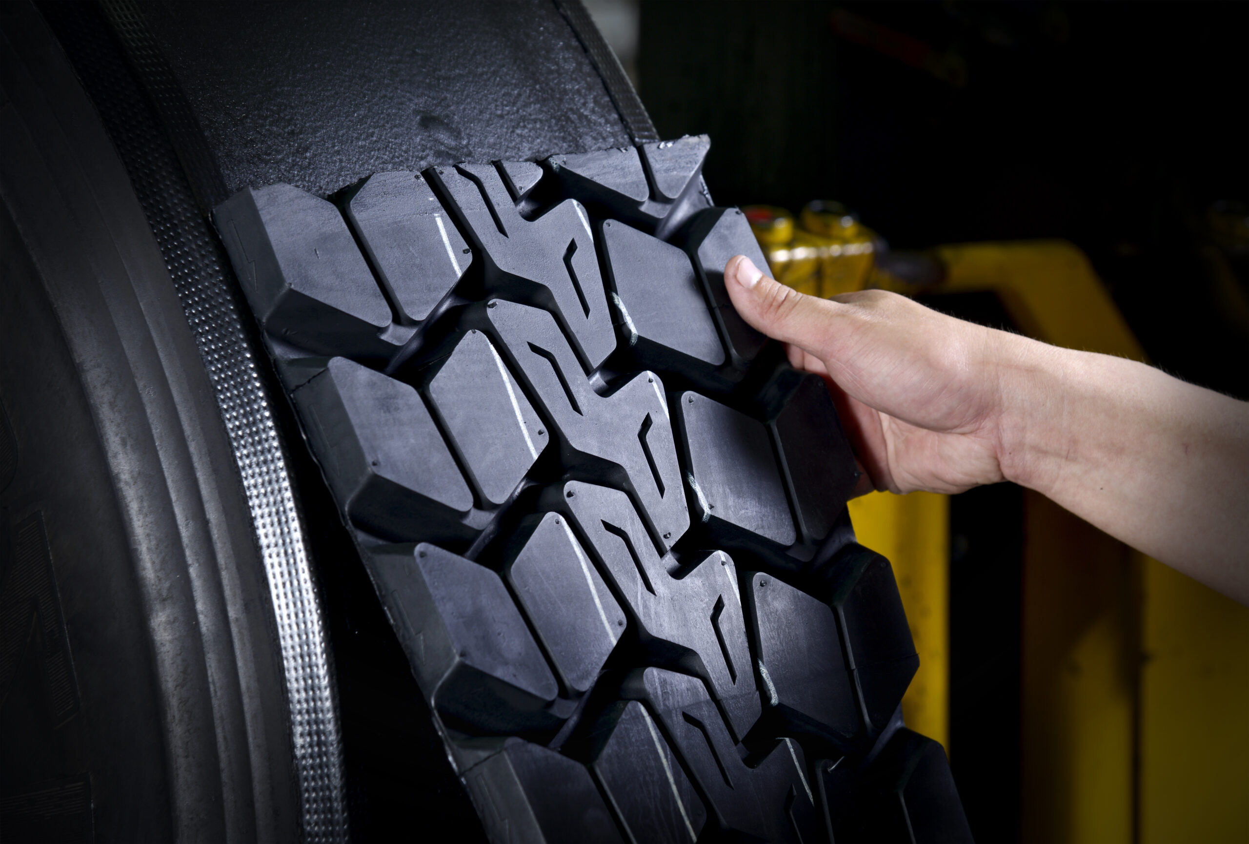 Worker sticking new rubber surface for tyre retread
